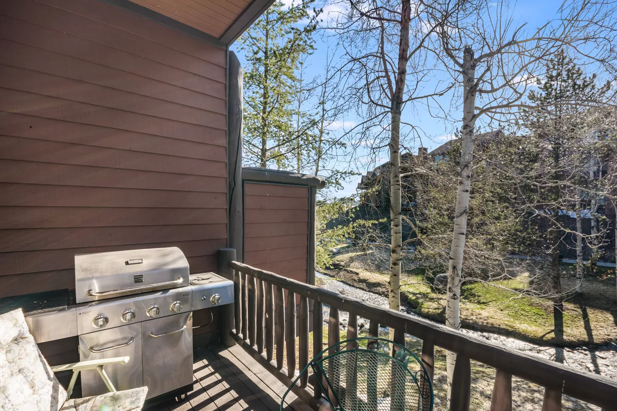 A spacious outdoor deck with a barbecue grill, comfortable seating, and views of the surrounding trees and landscape. The area invites relaxation and gatherings, connecting guests to the outdoors even when not on the slopes.
