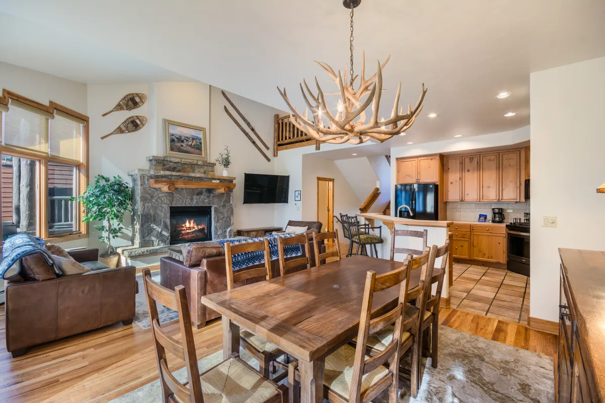 A spacious dining area is showcased here, complete with a large dining table beneath a glowing chandelier and an adjacent fireplace. The setting exudes warmth and is perfect for family gatherings or sharing memorable meals in a welcoming ambiance.
