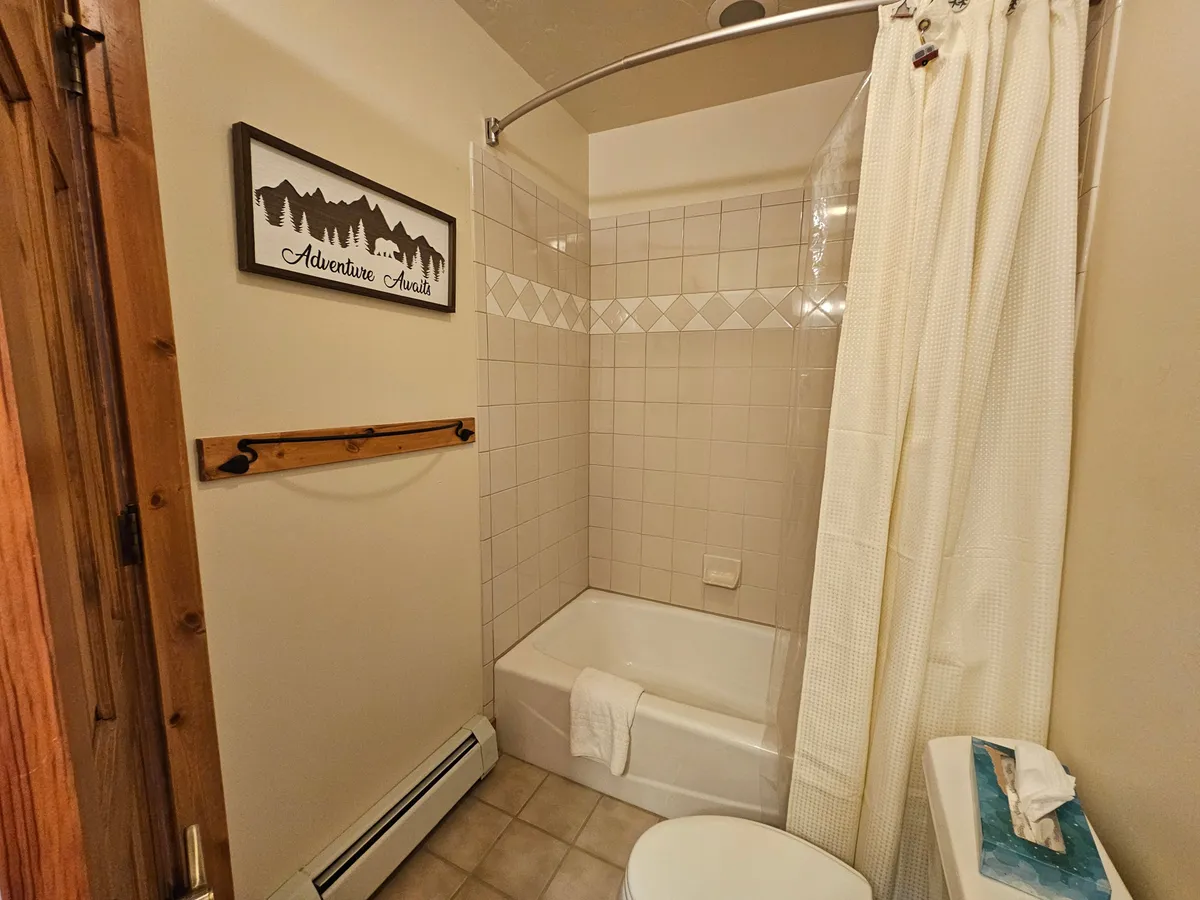 This image showcases a cozy shower area with a wooden towel rack and a decorative sign, evoking the comforts of home after outdoor adventures. The space feels warm and inviting, perfect for unwinding.